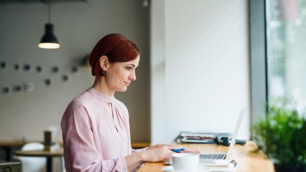A portrait of woman with coffee sitting at the table in a cafe, using laptop