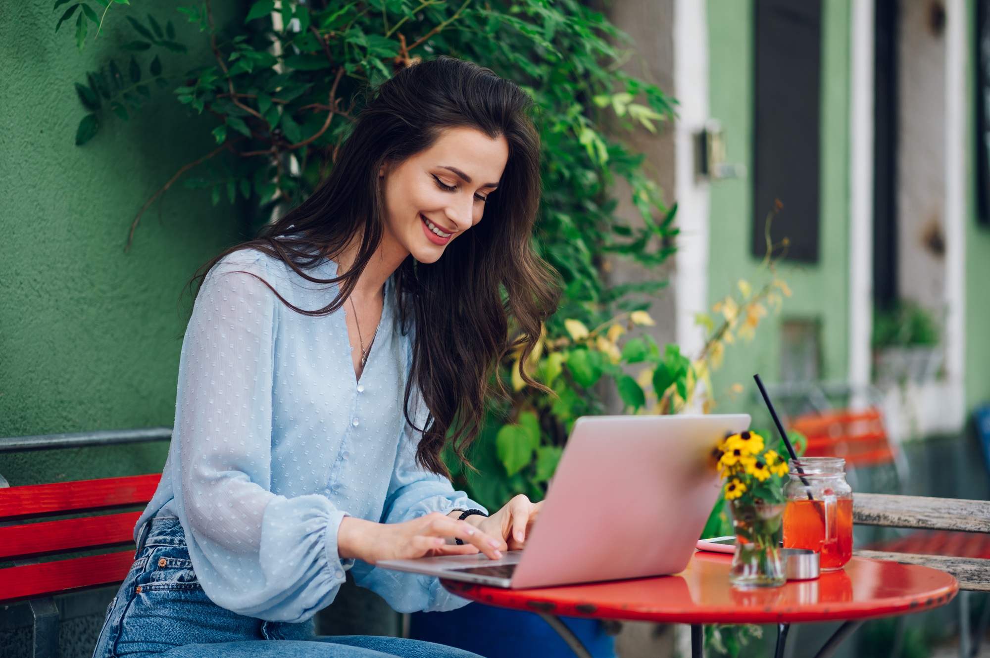 Beautiful woman sitting in a street cafe and using a laptop