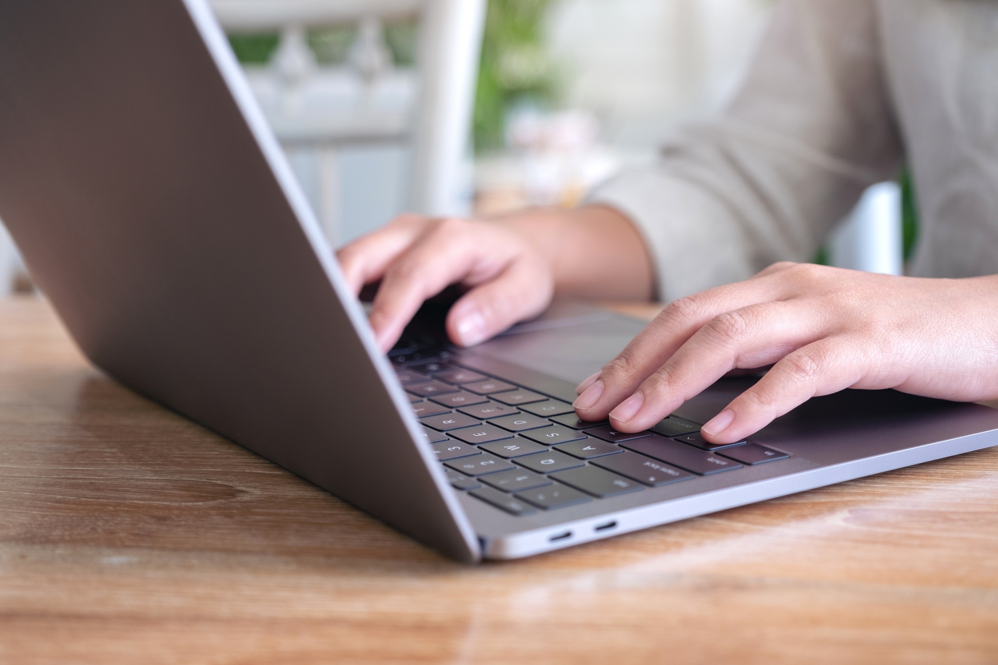 Closeup image of woman's hands using and typing on laptop keyboard on the table