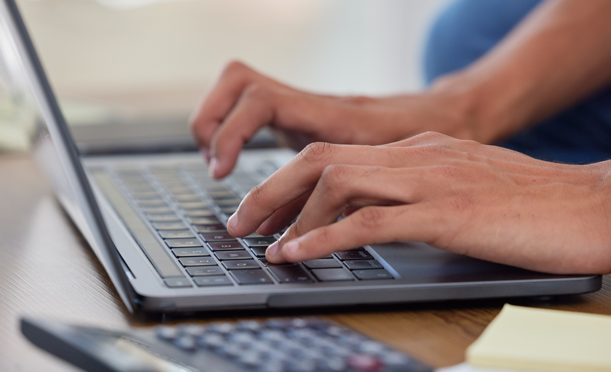 Hands, laptop keyboard and typing with finance, budget and person writing financial report with cal