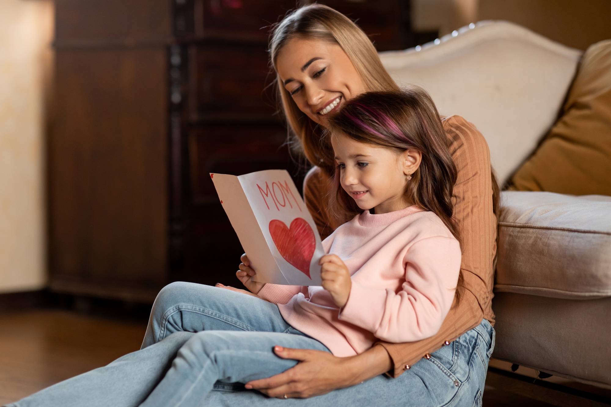 Happy daughter greeting mom with card, reading together