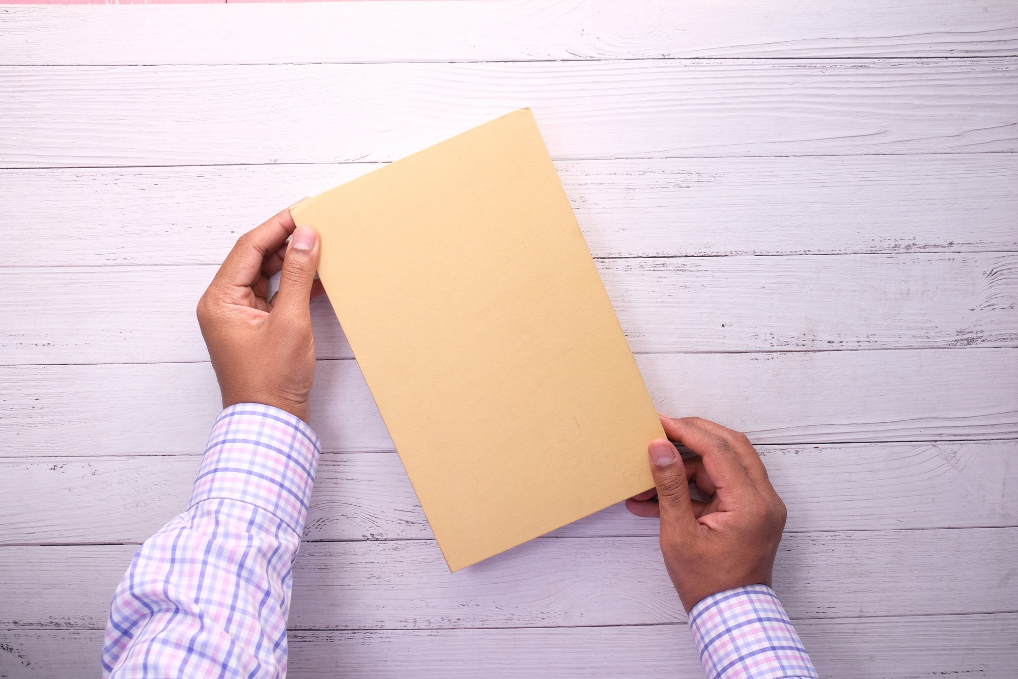 Man holding book with blank cover on white.