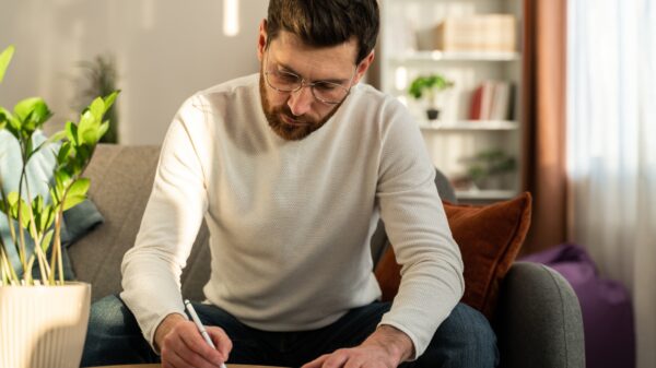 Serious man wearing glasses writing letter, notification, working with documents