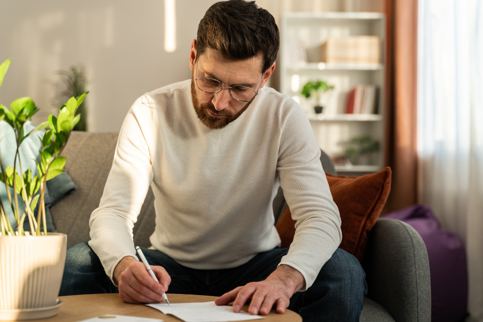 Serious man wearing glasses writing letter, notification, working with documents